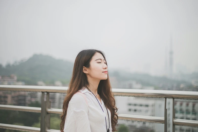 an asian woman standing on a roof next to a city