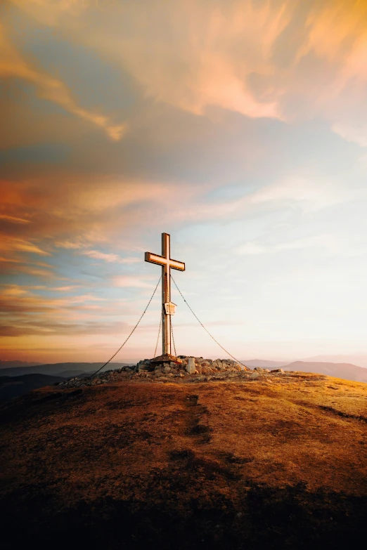 a cross sitting on the top of a hill