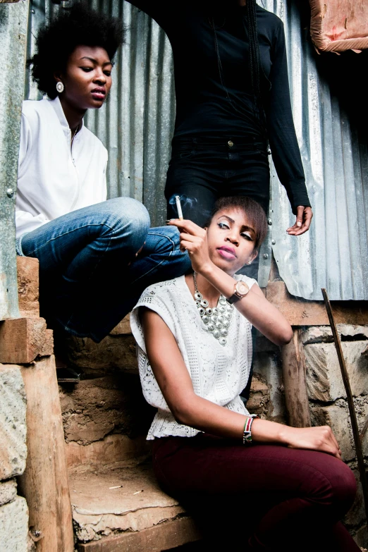 two woman sitting on steps while a man holds up a phone to a girl's ear