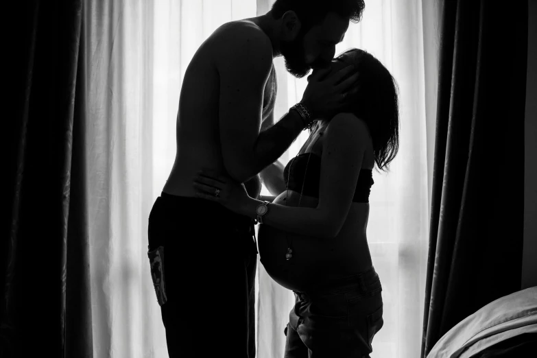 man and woman kiss while standing in a dark room