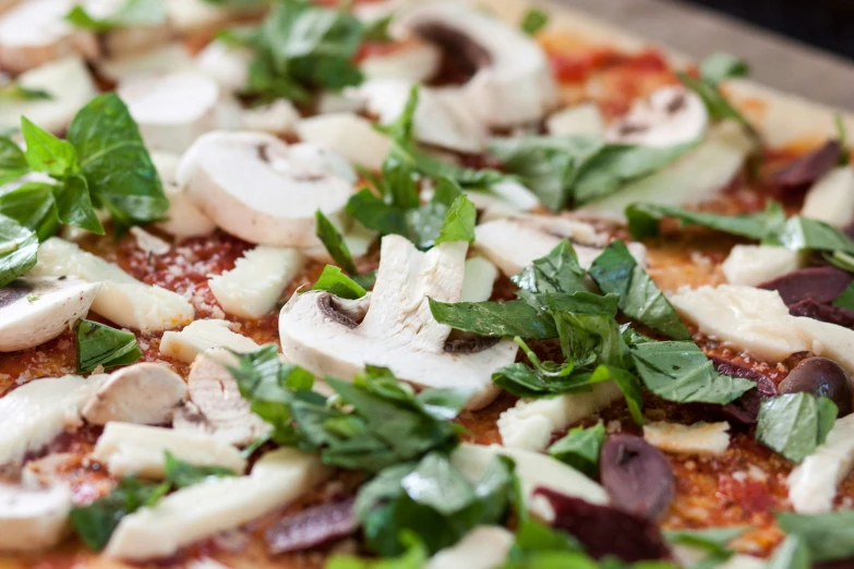 mushrooms and leaves atop pizza crust for consumption