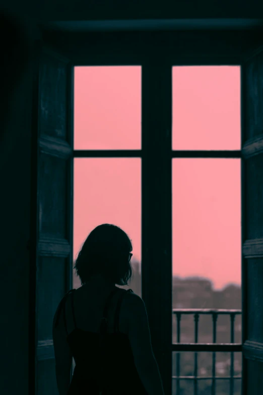 a woman looking out of a window into a dark room
