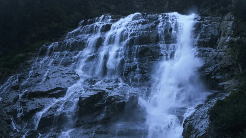 a waterfall surrounded by rocks and green forest