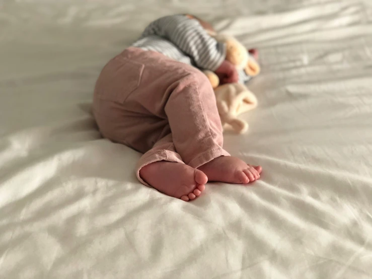 a little baby wearing pink pants on top of a bed