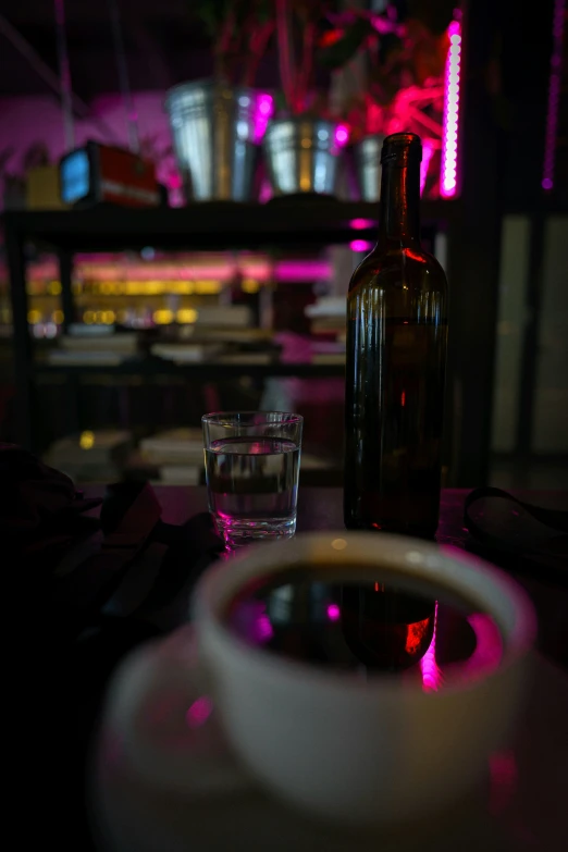 an empty glass on a table with a bottle next to it