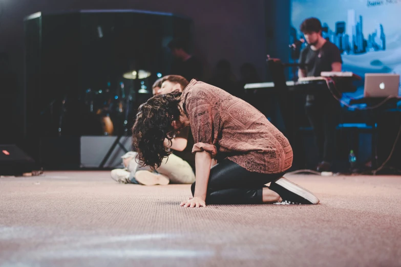 a girl sits on the floor with her head down