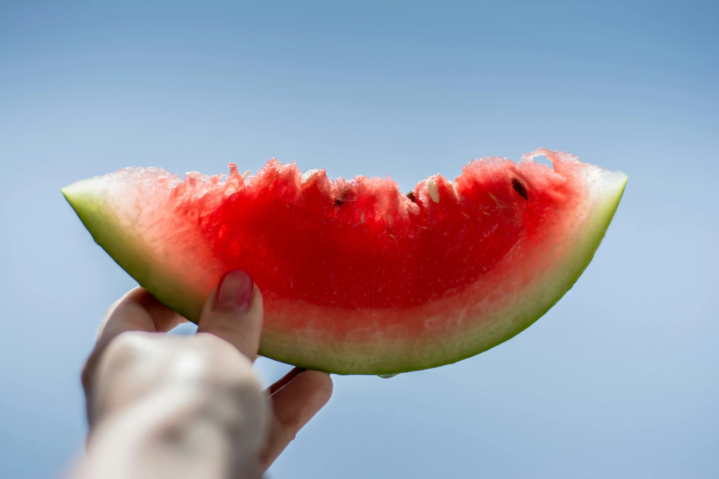 a watermelon slice being held up to the sky