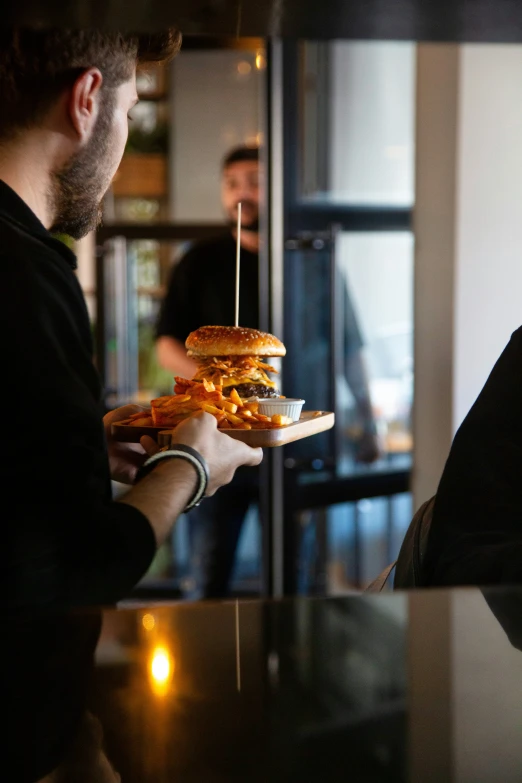 a man holding a cheeseburger in one hand and another person in the other