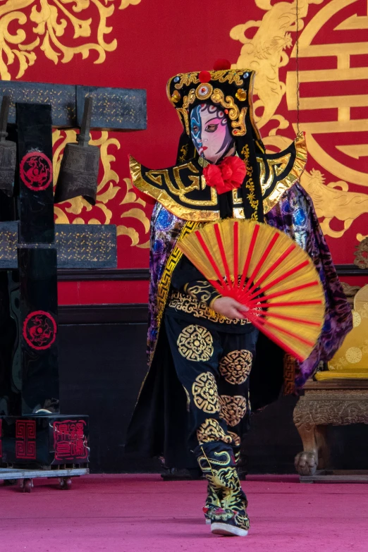 a woman in traditional clothing with a fan walks down the runway