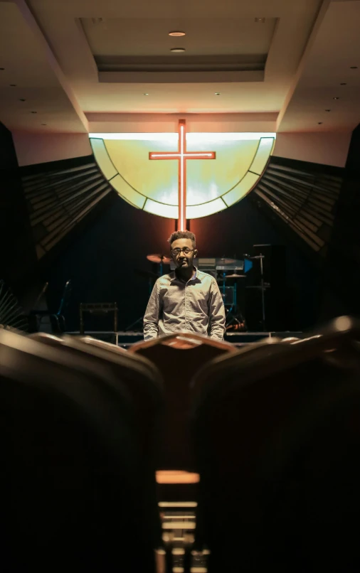 a man standing inside of a church next to a cross