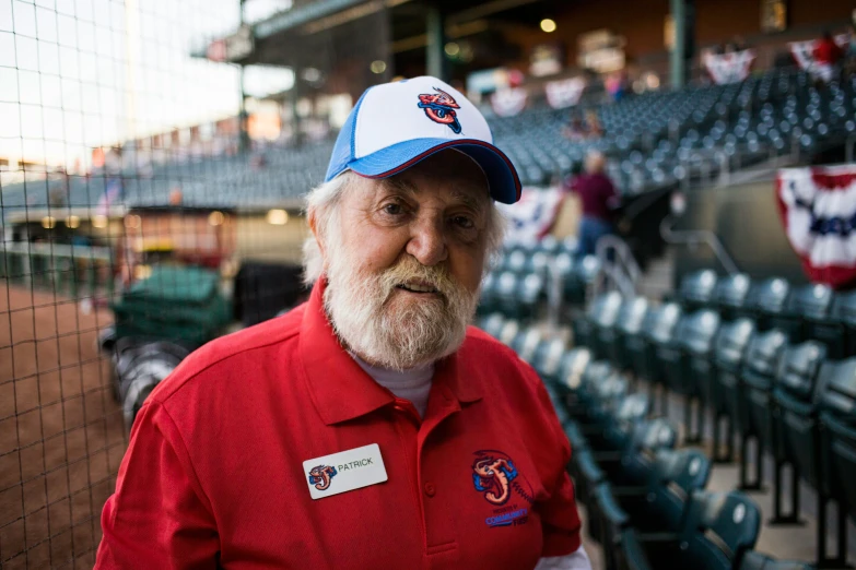 a man in a red shirt and white hat stands next to some seats