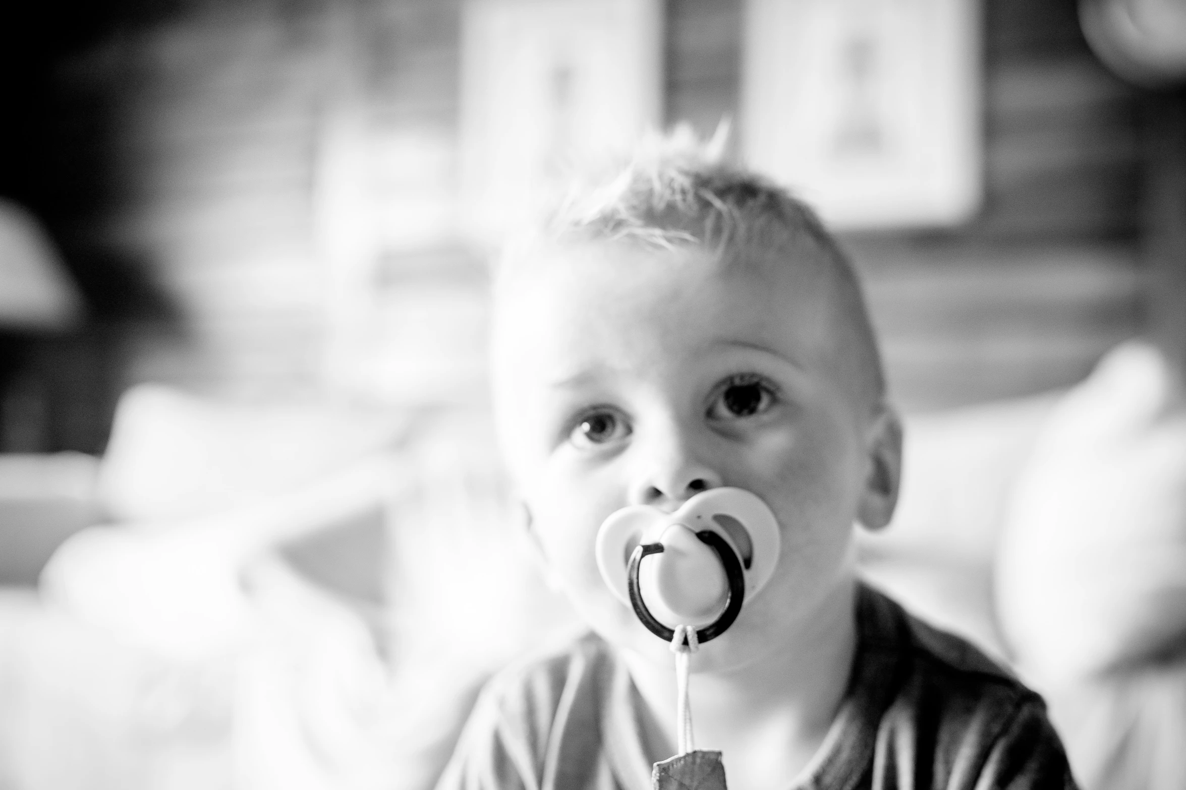 a black and white po of a toddler with a dummy
