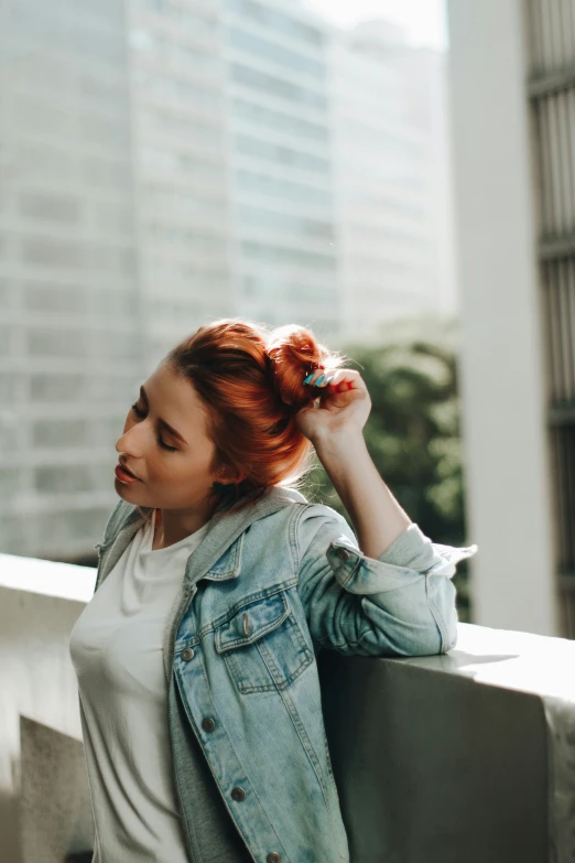 a woman standing by the ledge holding her hair in an upside down bun