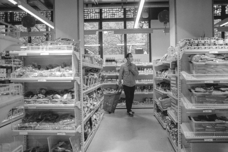 person standing in aisle of a grocery store with a basket of food