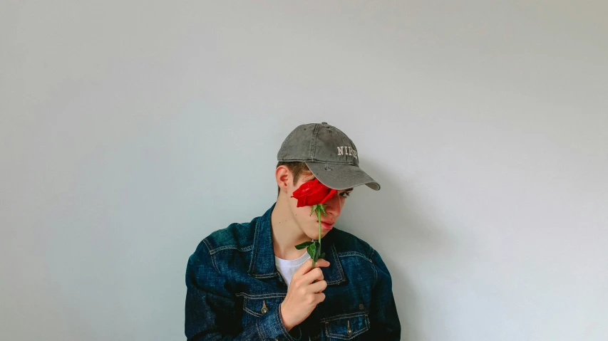 the man wearing jeans is holding a rose in his hand