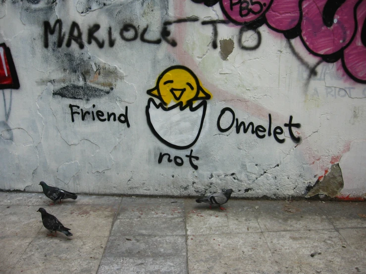 two birds sit on the sidewalk near a graffiti wall