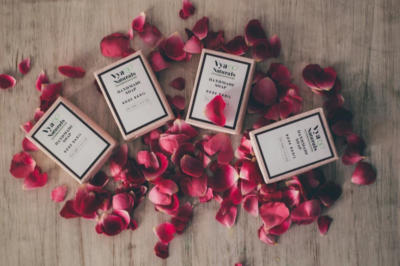 five wooden stamps with some writing sitting on a wood table surrounded by rose petals