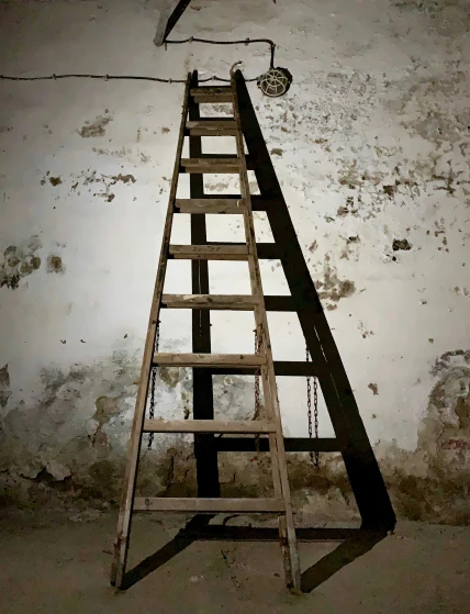 a wooden ladder suspended on a white wall