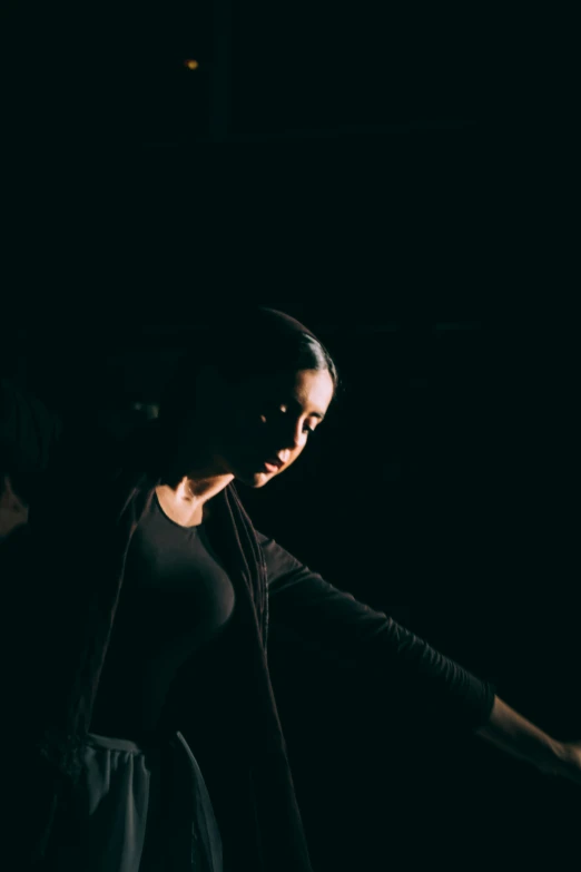 a woman standing in the dark, wearing black