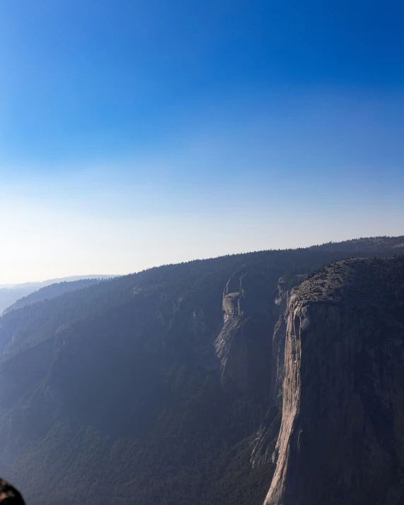 a man on a mountain flying an orange kite