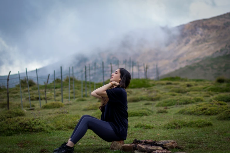 a person sitting down in a field next to mountains