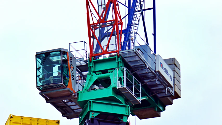 a green tower crane with two yellow and one blue signs