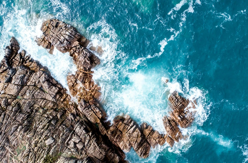 aerial view of rocks with large breaking waves on ocean