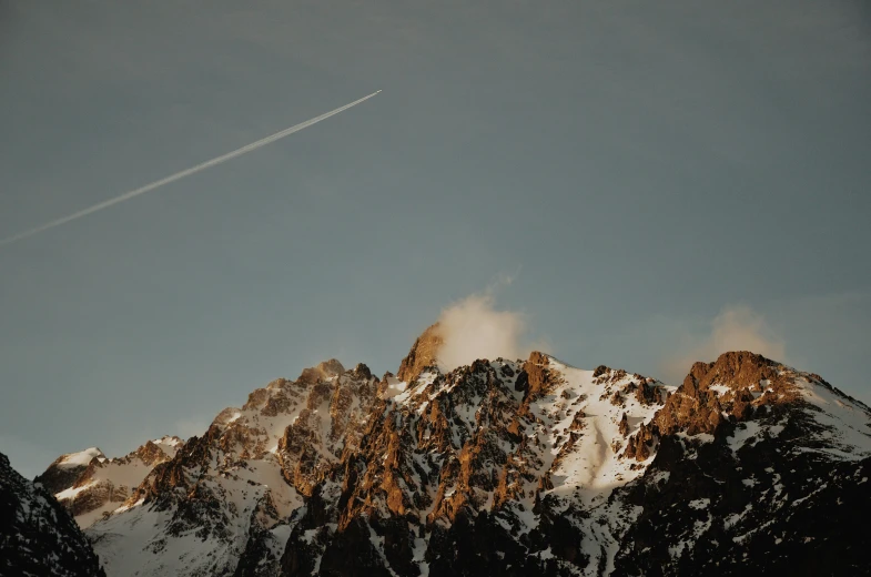 a jet flying in the sky over a mountain