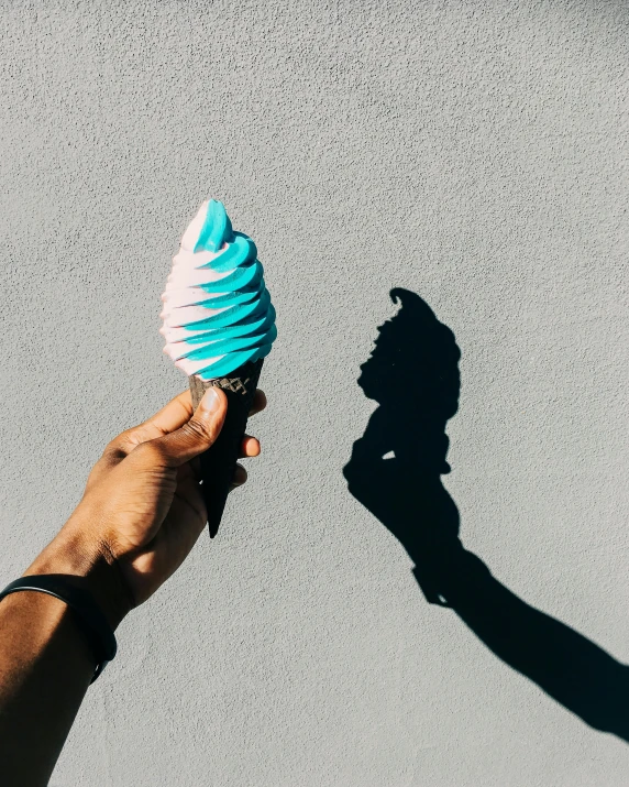 a person's hand holding onto a ball and a shadow