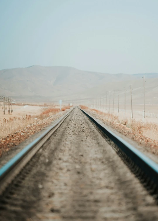 a train track in the desert with mountains behind it