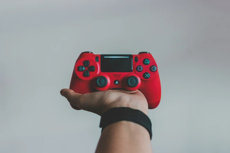 a hand holding a red game controller with the screen showing