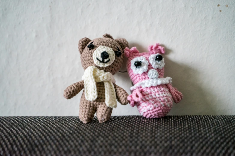 two knitted stuffed animals with one wearing a pink sweater