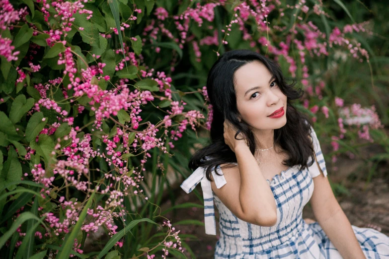 a pretty young lady sitting in front of flowers