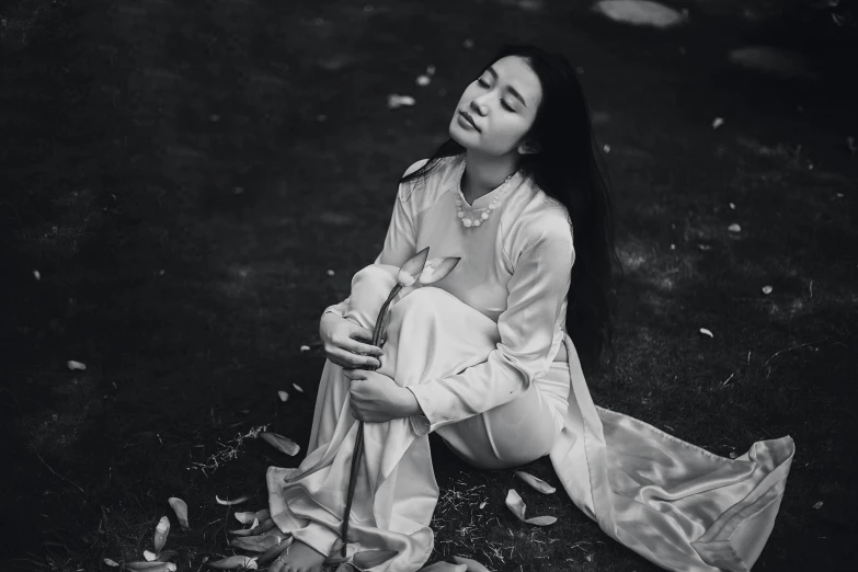 the young woman sits in a field while looking up into the air