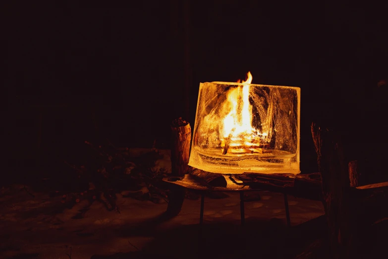 a lit lit up glass candle in a dark setting