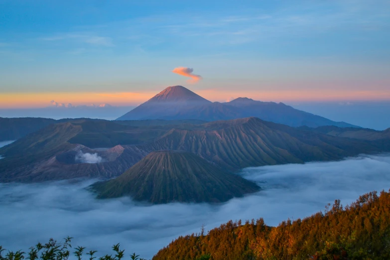 the view from top of the mountain shows the forest, below, and clouds