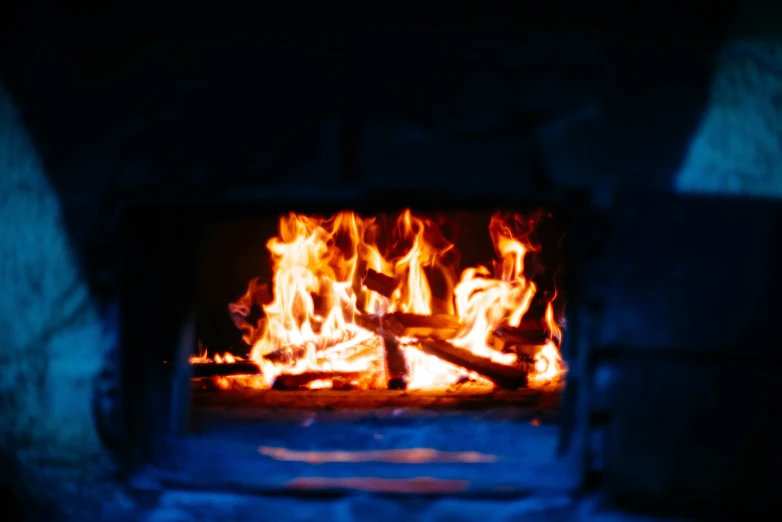 a fire burning in a brick oven with dark walls