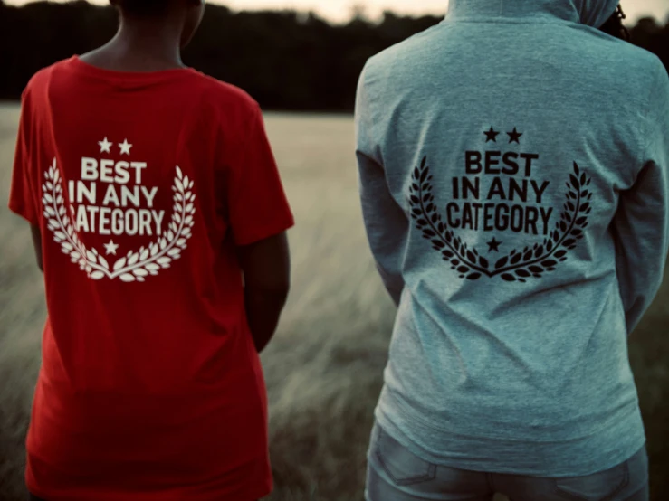 the two people wearing red and gray shirts are looking at a field