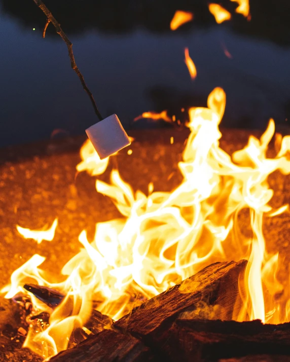 closeup of flames with a campfire in the background