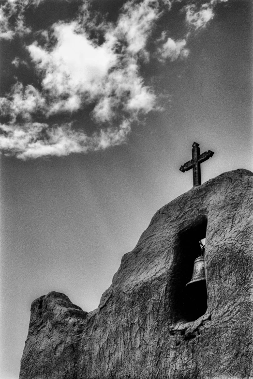 a cross on top of a hill under a cloudy sky