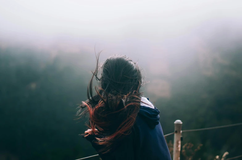 a person stands on a mountain top in fog