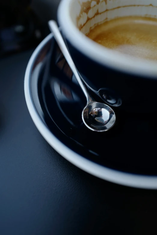 a cup and spoon on a black table