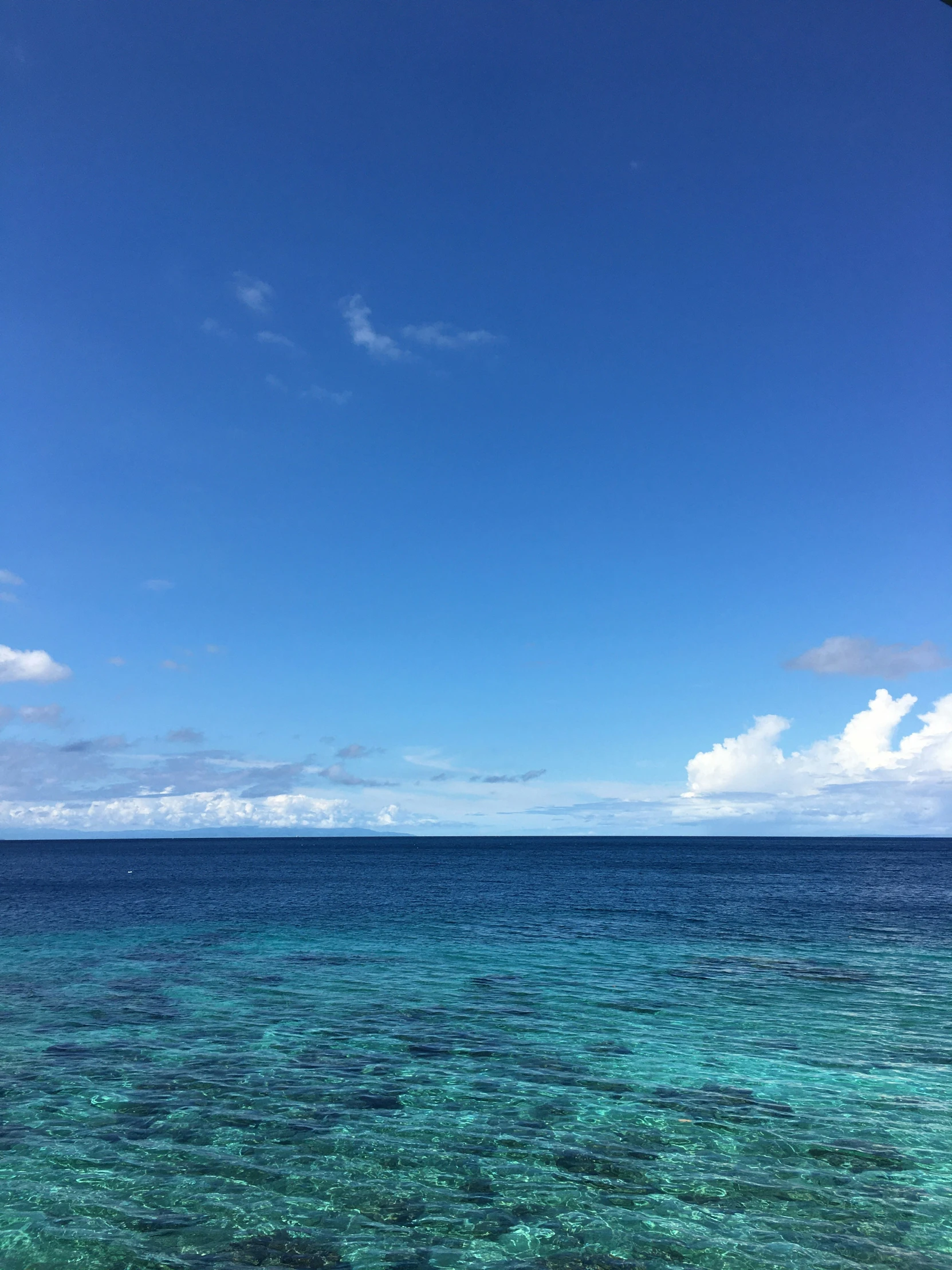 calm ocean with blue sky and white clouds