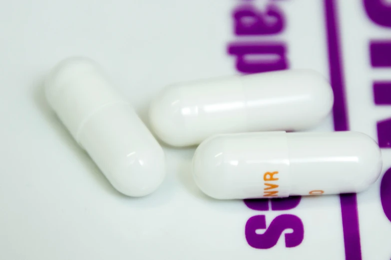 a group of three pills with a purple and white sticker