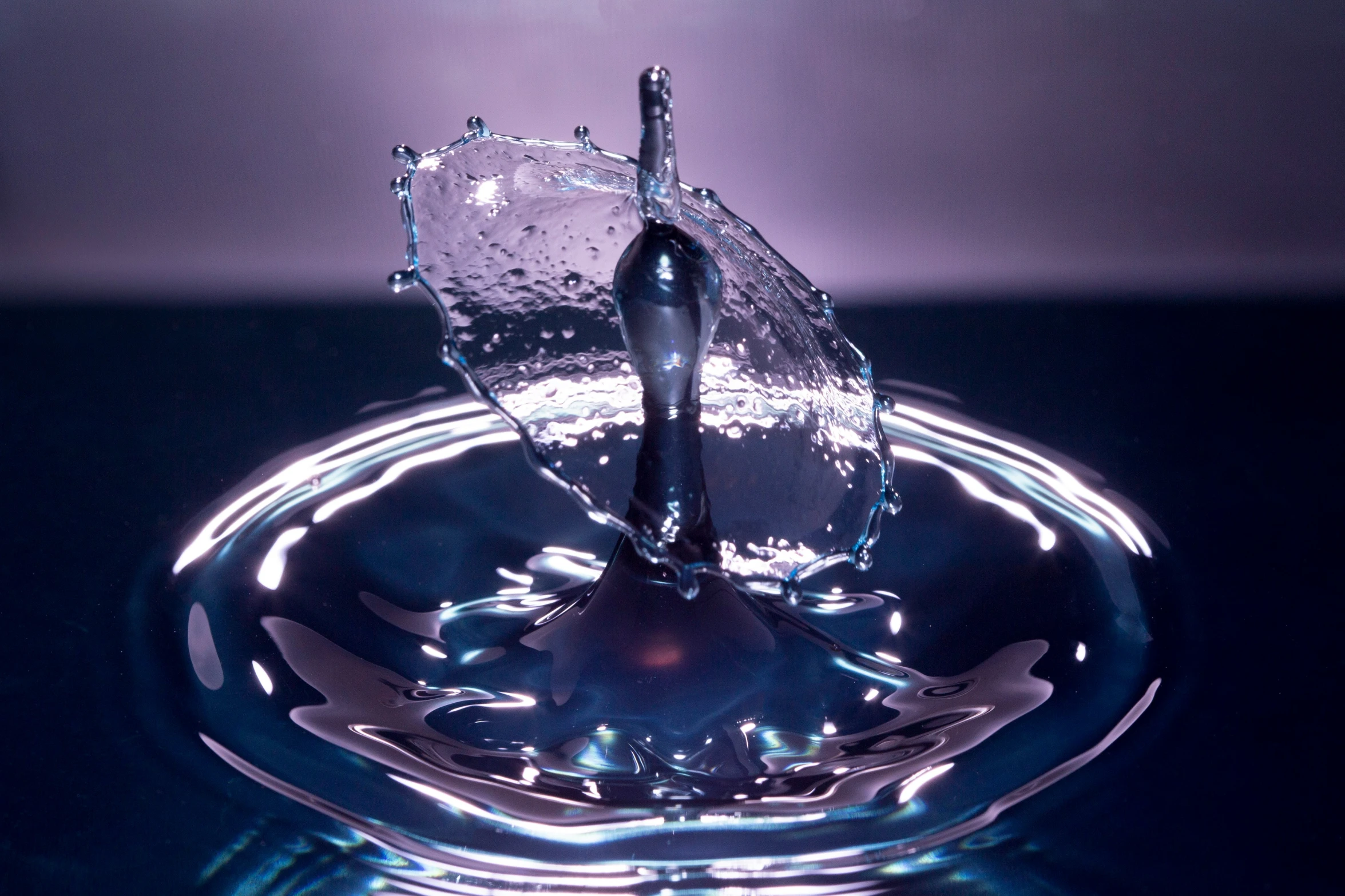 a glass on a black table with a small splash of water