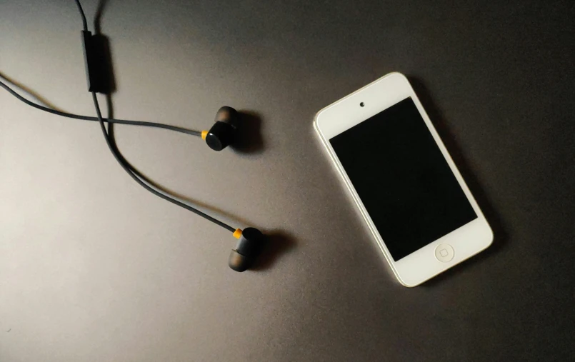 a white and black cellphone some headphones and earbuds