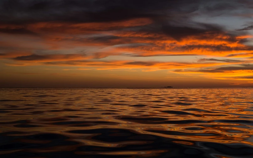 a large body of water with a sunset in the background