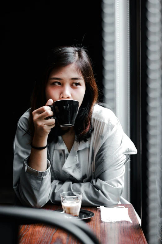 a woman holding up her coffee cup in front of her face