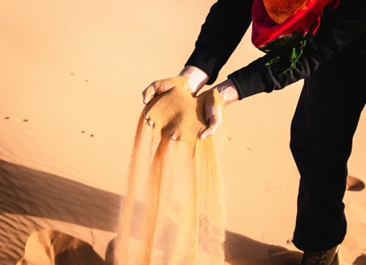 there is a man kneeling down with a sand dune