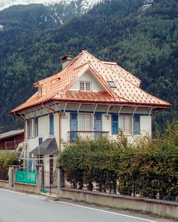 an old white home with red tiled roof sits beside an old stone street